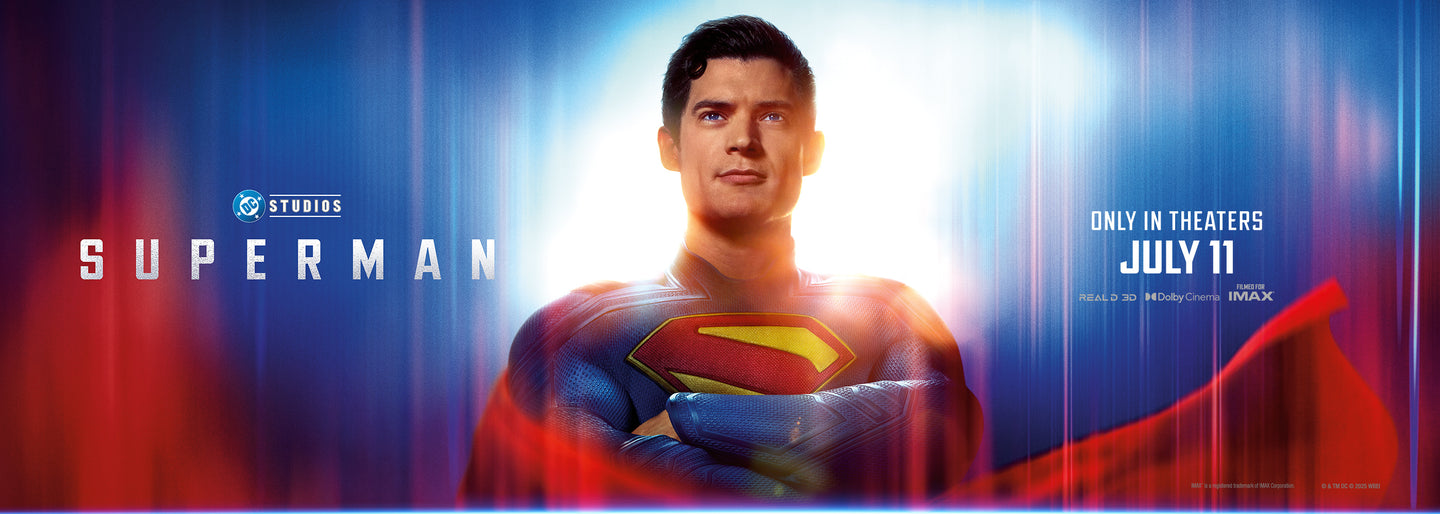 A promotional poster for the upcoming Superman movie by DC Studios. Superman, portrayed by a new actor, stands confidently with his arms crossed, illuminated by a bright white and blue light behind him. He wears the classic blue suit with a red and yellow "S" emblem on his chest and a flowing red cape. The text reads: "DC Studios SUPERMAN" on the left, and "ONLY IN THEATERS JULY 11" on the right, alongside logos for RealD 3D, Dolby Cinema, and IMAX.