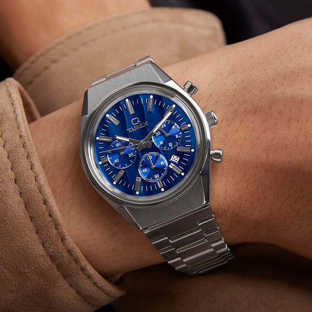 Close-up angled view of the Q Timex Falcon Eye Chronograph showing the polished steel case, pushers, and metallic blue chronograph dial with applied indices and subdials.