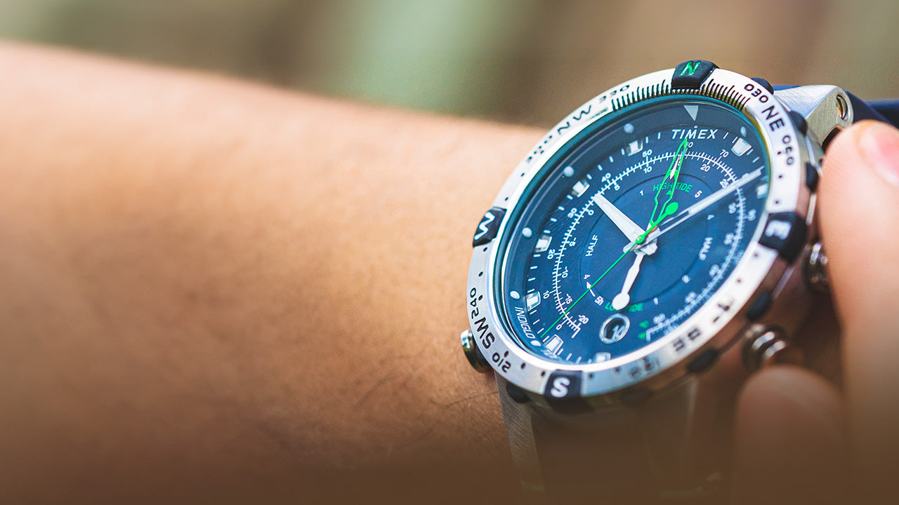 Angled wrist shot of the Timex Expedition Tide-Temp-Compass watch with blue dial, compass bezel, luminous hands, and green tide indicators, emphasizing its rugged outdoor design.
