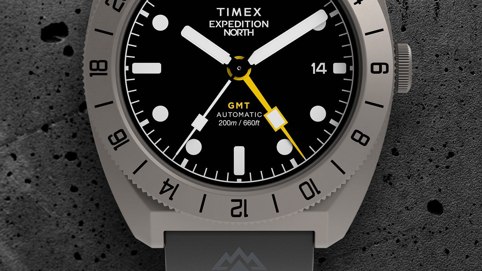 Macro shot of the Timex Expedition North GMT Titanium Automatic dial and bezel, focusing on the yellow GMT hand, 24-hour bezel markers, and luminous hour indices.
