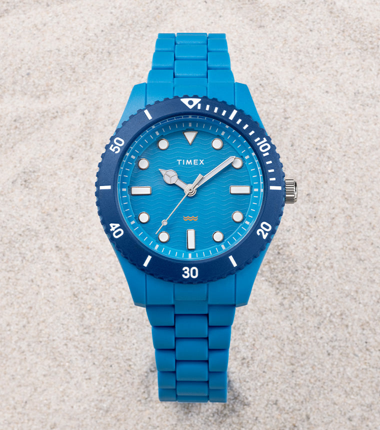 Timex Legacy #tide 42mm Recycled Plastic Bracelet Watch BLUE variant beautifully laid against a white sand in the beach