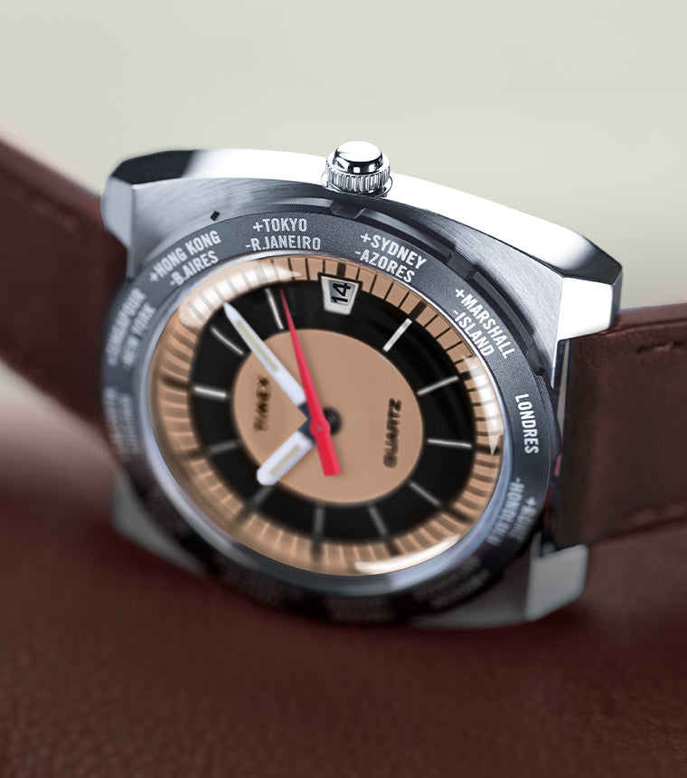 Close-up shot of a Timex world time wristwatch featuring a dual-tone copper and black dial, date window at the 12 o'clock position, and a rotating bezel marked with major global cities such as Tokyo, Sydney, Londres, and Hong Kong. The watch has a polished stainless steel case and a brown leather strap.