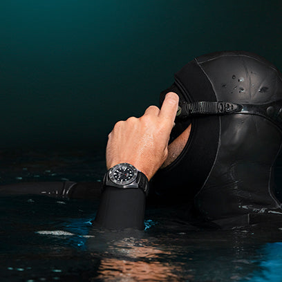 Diver in a black wetsuit adjusts their mask at the water’s surface, wearing the Timex Deepwater Meridian 200 on their wrist.