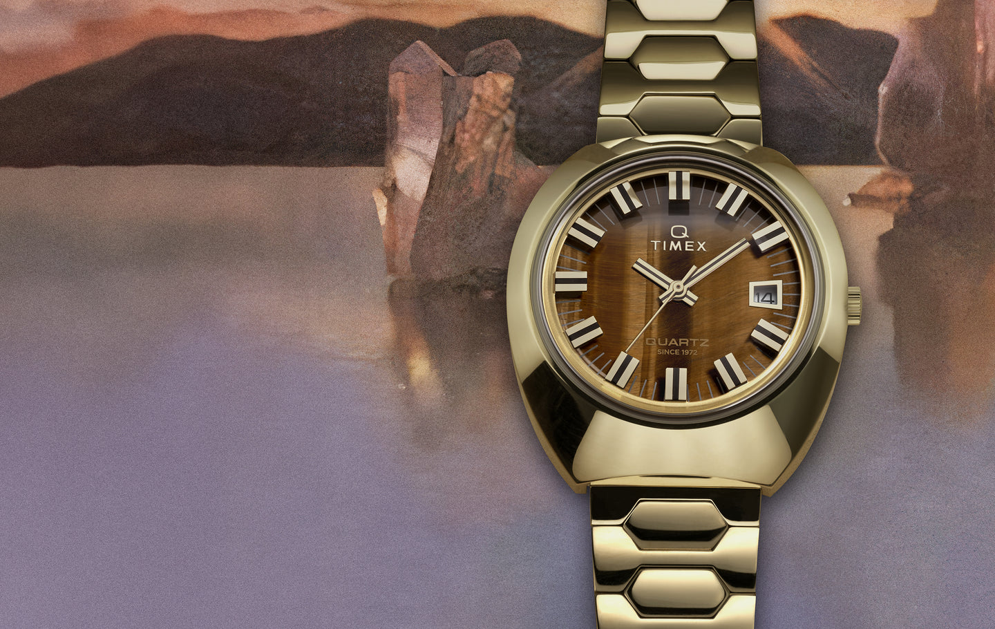 Timex Q wristwatch with a gold-tone case and bracelet, featuring a tiger’s eye-pattern dial, bold white hour markers, date window at 3 o’clock, and set against a soft, painted landscape background.