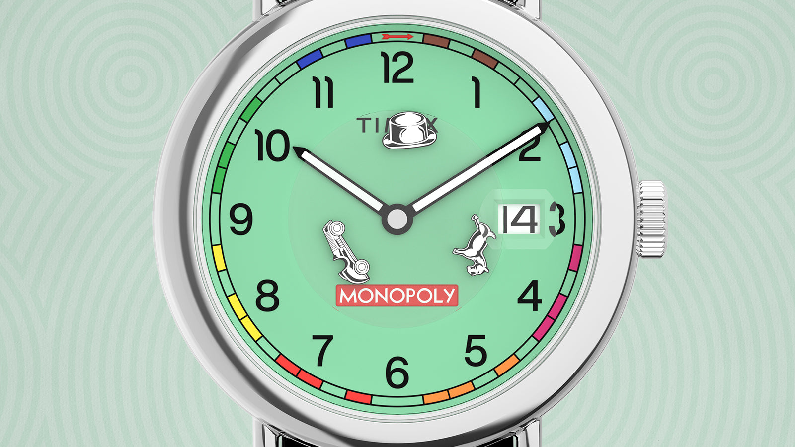 Close-up of the Timex x Monopoly Weekender watch face showing detailed Monopoly motifs — the top hat under the Timex logo, silver car and dog tokens, and the Monopoly logo in red. The mint-green dial is bordered with property colors from the Monopoly board and features a date window at 3 o’clock.
