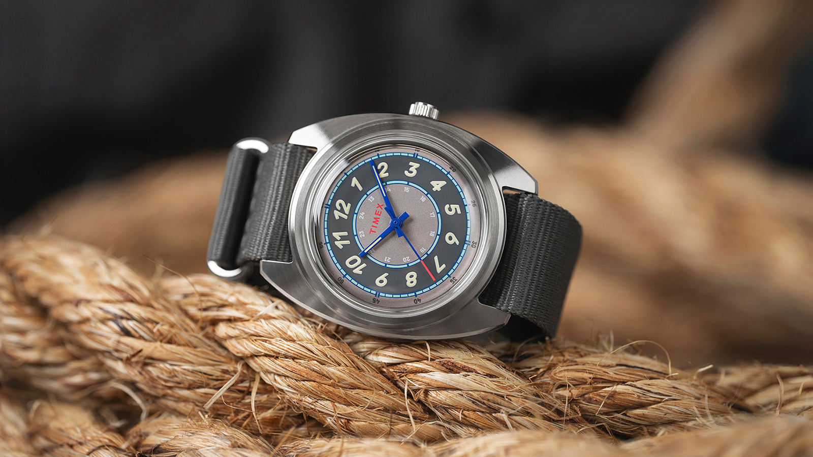 A bright close-up of the Timex x Worn & Wound Storm resting on coiled rope, displaying the brushed stainless-steel case and blue seconds hand.
