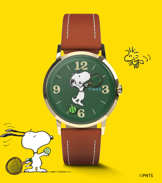 Peanuts® x Timex Marlin® Hand-Wound watch with Snoopy playing tennis on a green dial, gold-tone case, and brown leather strap, set against a bright yellow background with Snoopy and Woodstock illustrations.