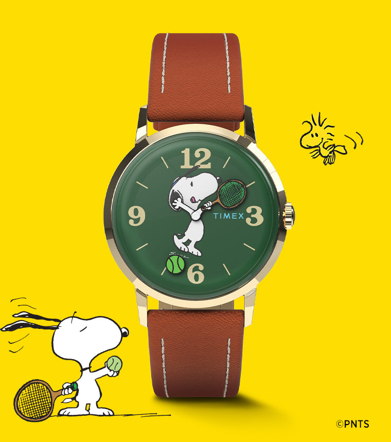 Peanuts® x Timex Marlin® Hand-Wound watch with Snoopy playing tennis on a green dial, gold-tone case, and brown leather strap, set against a bright yellow background with Snoopy and Woodstock illustrations.