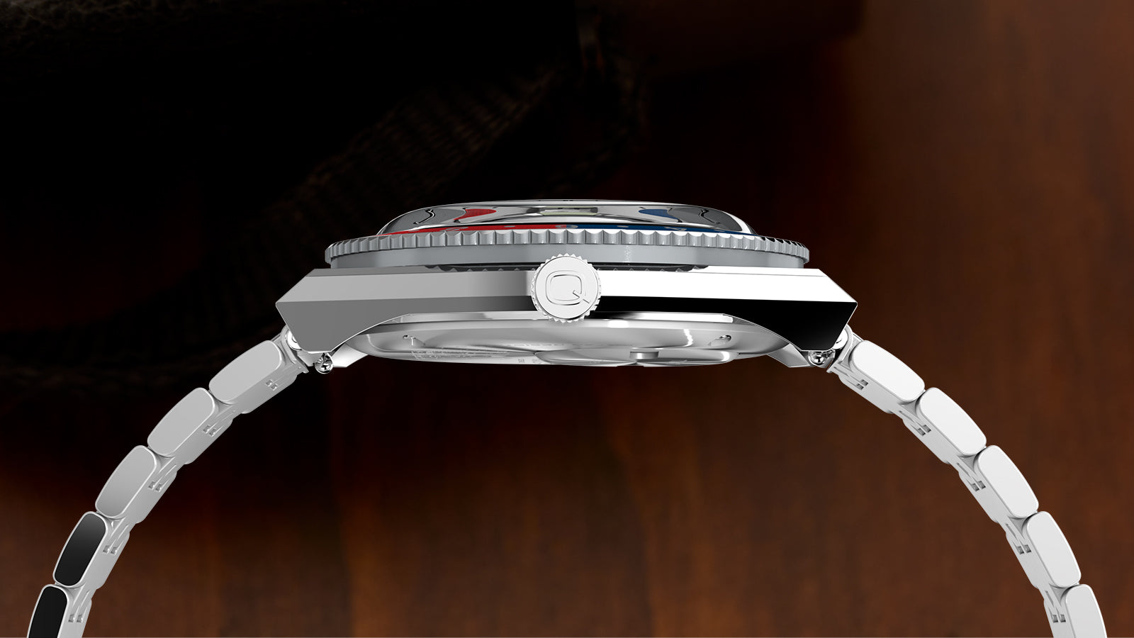 Side view of the Timex x Peanuts® Q Timex® GMT watch highlighting the polished stainless-steel case, the red and blue rotating bezel, and the “Q” crown logo, emphasizing the classic 1970s-inspired case geometry.