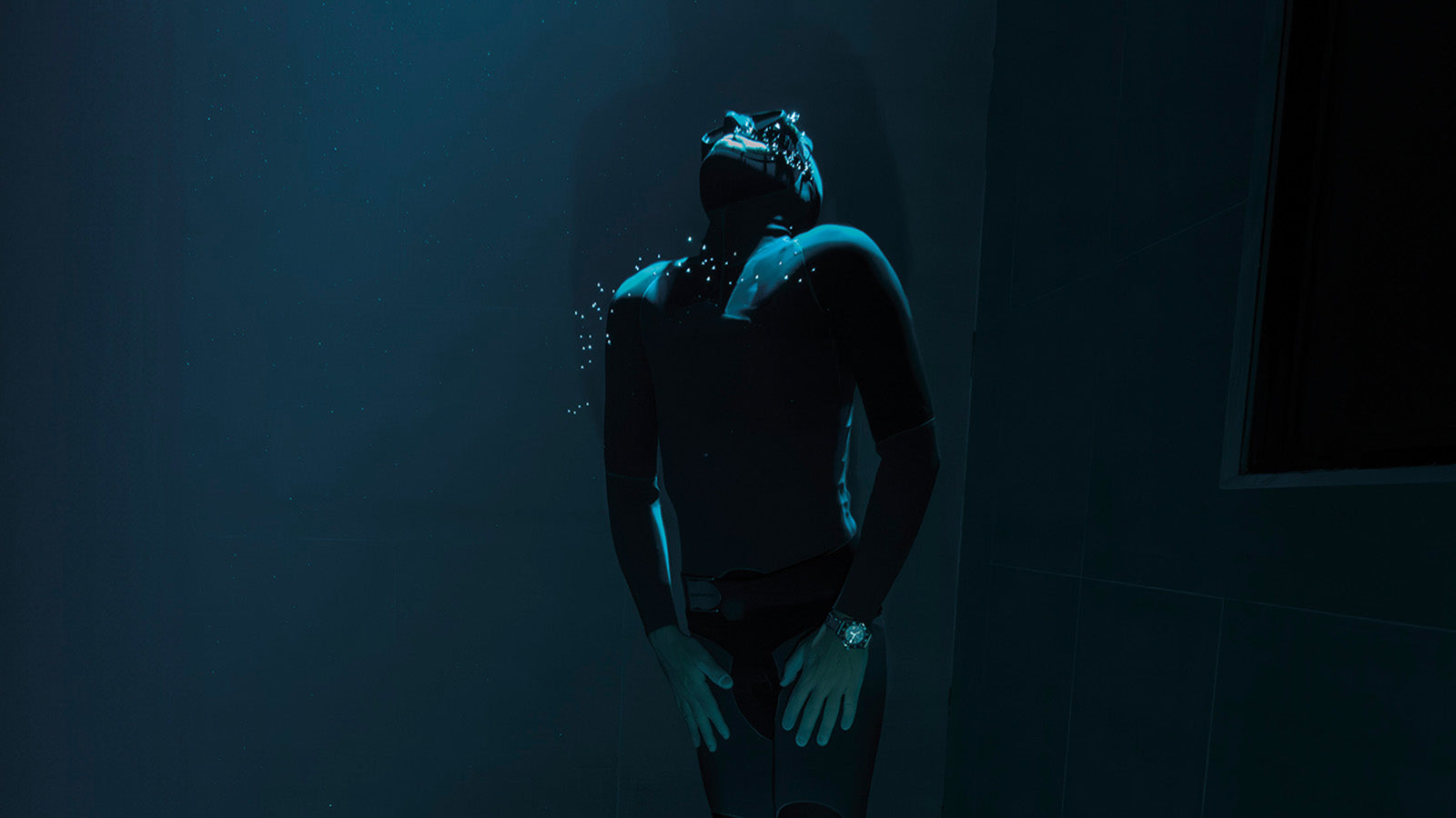 Freediver submerged underwater wearing the Timex Deepwater Reef 200, the glow of the watch visible through dim blue light, symbolizing endurance under pressure.