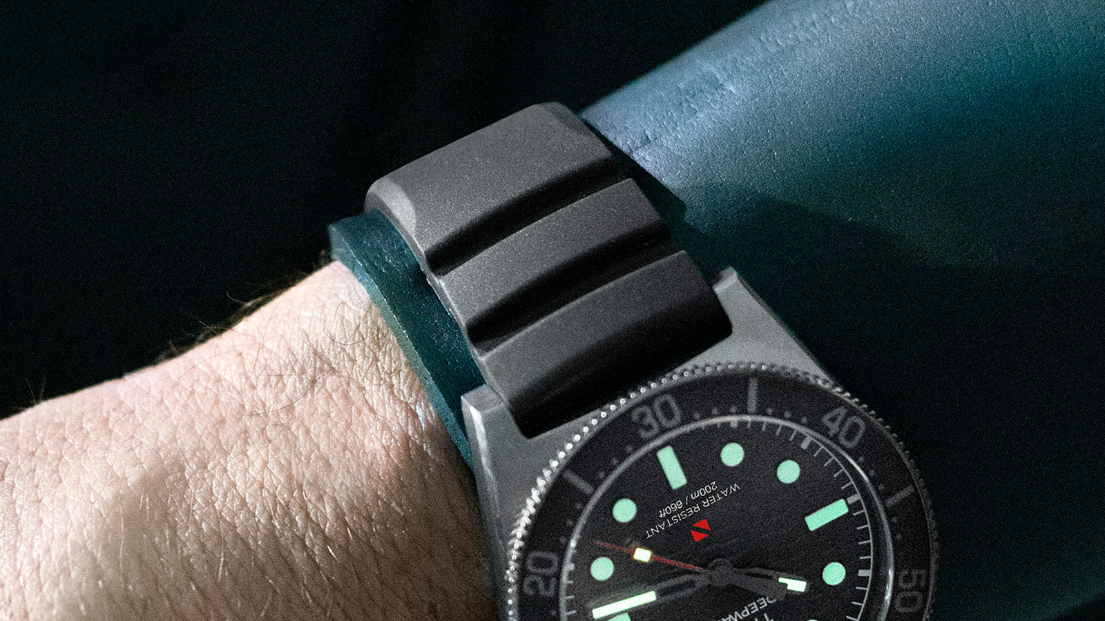Detailed macro view of the Timex Deepwater Reef 200’s black rubber strap and brushed titanium-finish lugs, highlighting its rugged dive-ready design.
