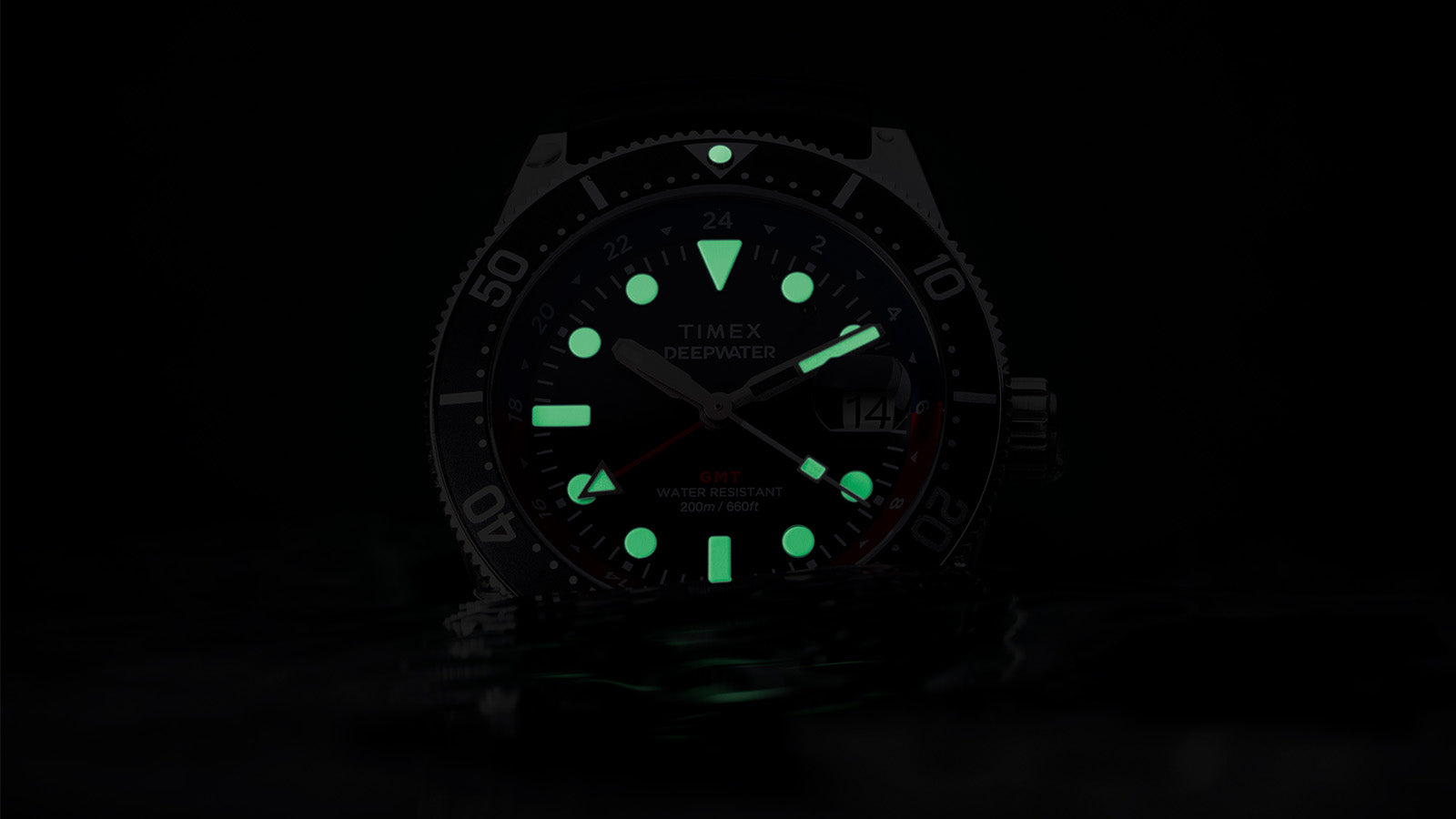 Timex Deepwater Reef 200 GMT glowing in darkness, showing bright green luminescent markers and hands for underwater visibility.