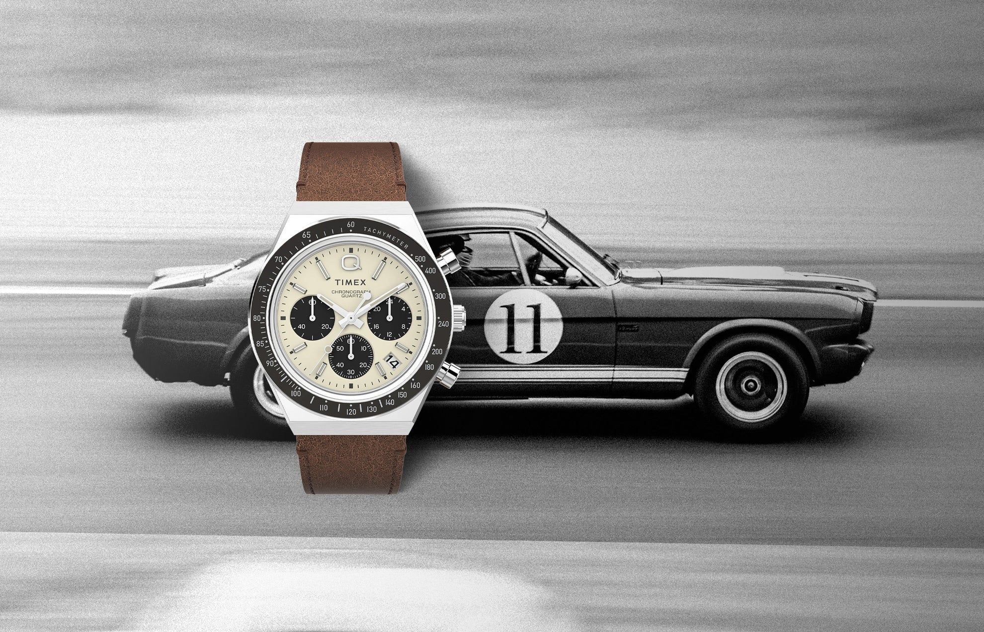 Q Timex Chronograph watch with a cream dial, black sub-dials, and brown leather strap displayed over a vintage racing car background, evoking a classic motorsport aesthetic.