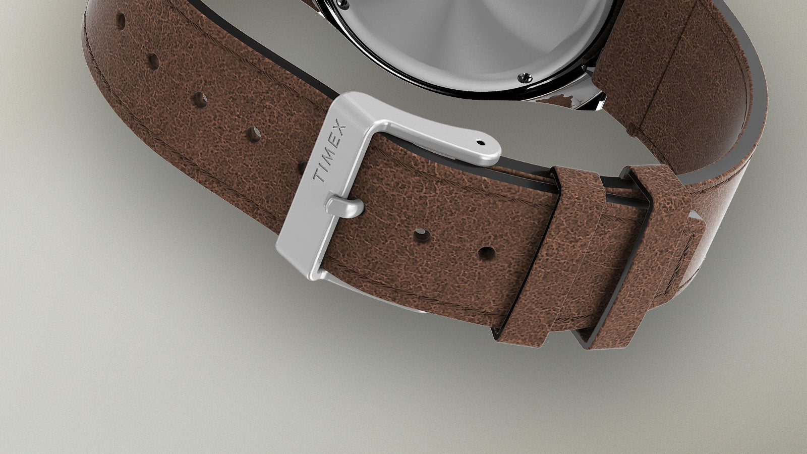 Close-up of the Q Timex Chronograph brown leather strap and silver buckle engraved with the Timex logo.