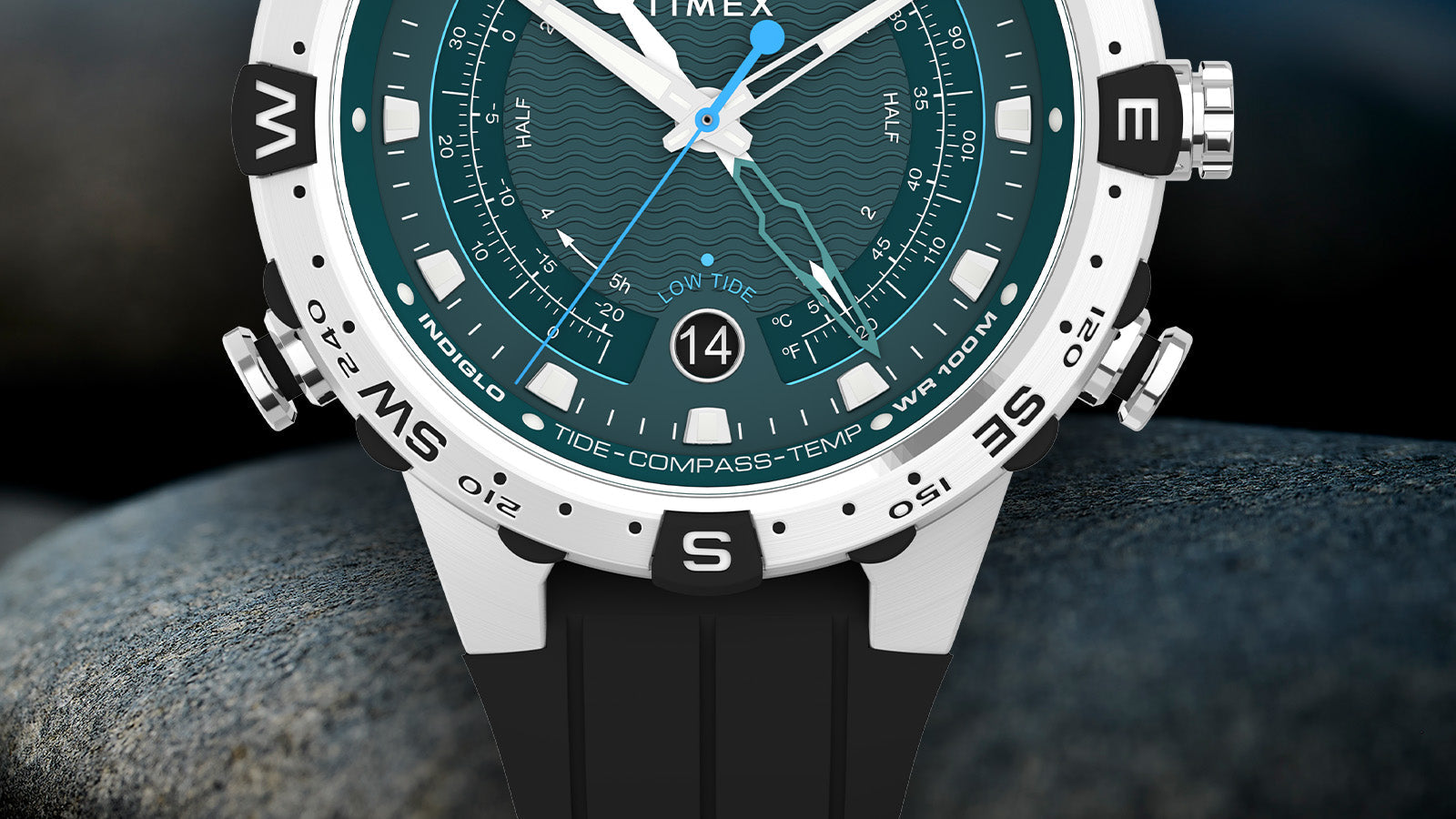 Close-up of the bottom half of the Timex Expedition Tide-Temp-Compass showing compass bezel, “Tide-Compass-Temp” text, teal dial with wavy pattern, and round date window at 6 o’clock.