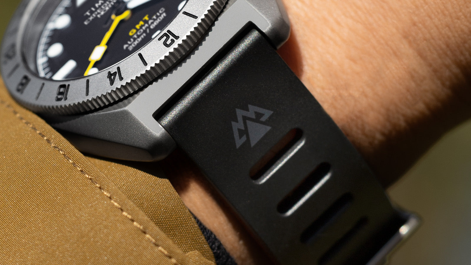 Close-up of the Timex Expedition North GMT Titanium Automatic strap and lugs, showcasing the black rubber strap with the Expedition North mountain logo.