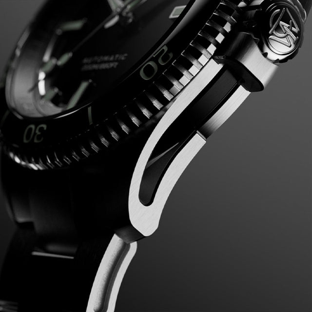 Macro side view of Timex Atelier watch case with brushed stainless steel finish, detailed crown engraved with "T" logo, and knurled bezel edge.