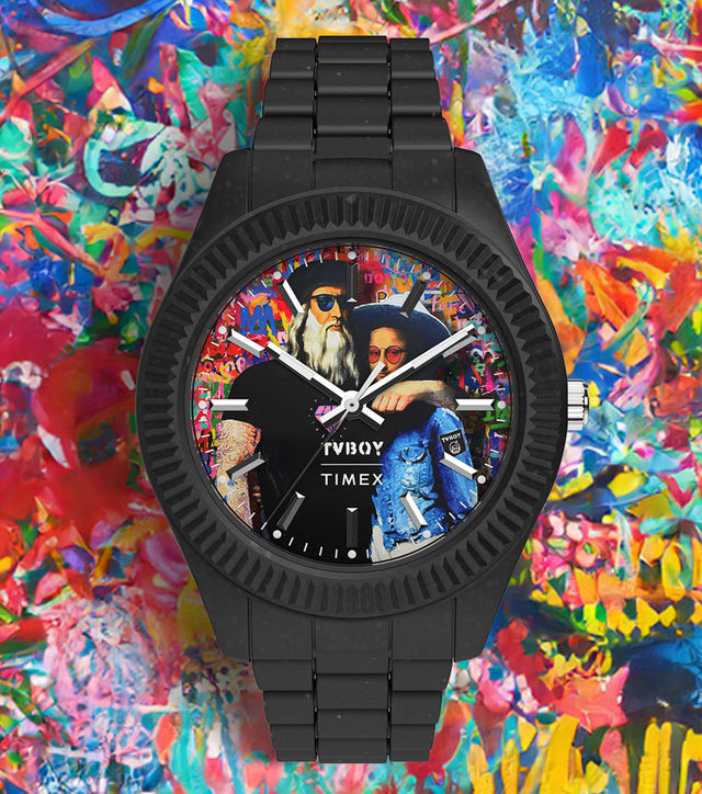 Timex Legacy Ocean x TVBOY watch with a matte black case and bracelet made from #tide ocean material. The colorful watch dial features a graffiti-style artwork of two figures against a vibrant, multicolored background symbolizing creativity and modern street art.