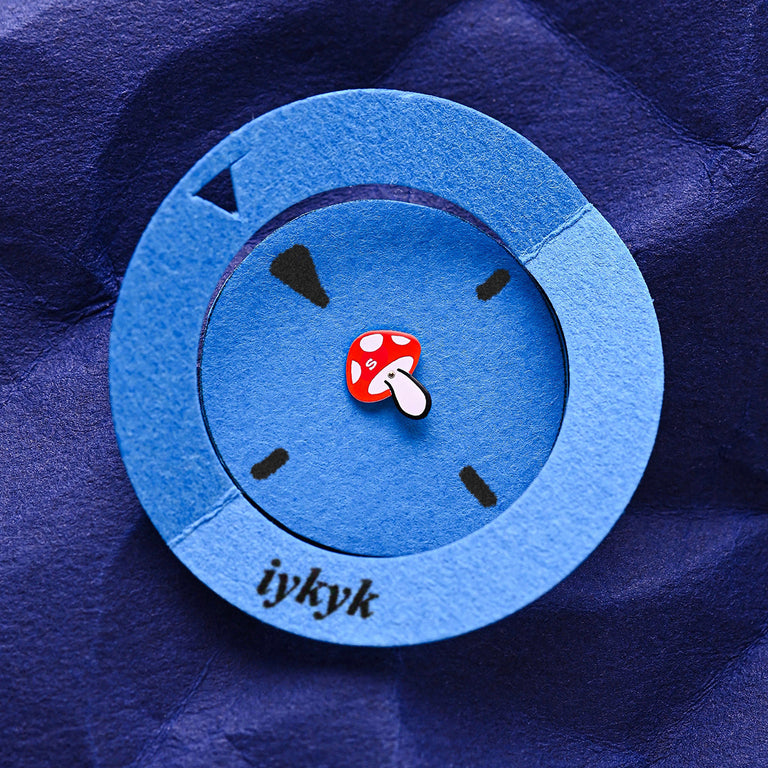 A paper art version of the Q Timex watch face, with a blue circular cutout and a red mushroom seconds hand on a deep blue textured background, featuring the word “iykyk.”