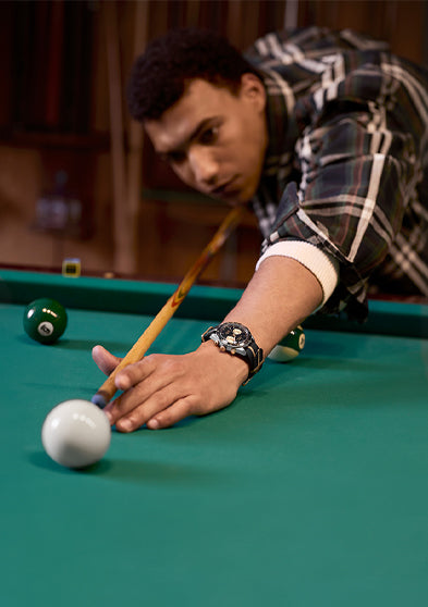 Man wearing the Timex Waterbury Heritage Chronograph taking a pool shot, showcasing the watch’s sporty and refined design.
