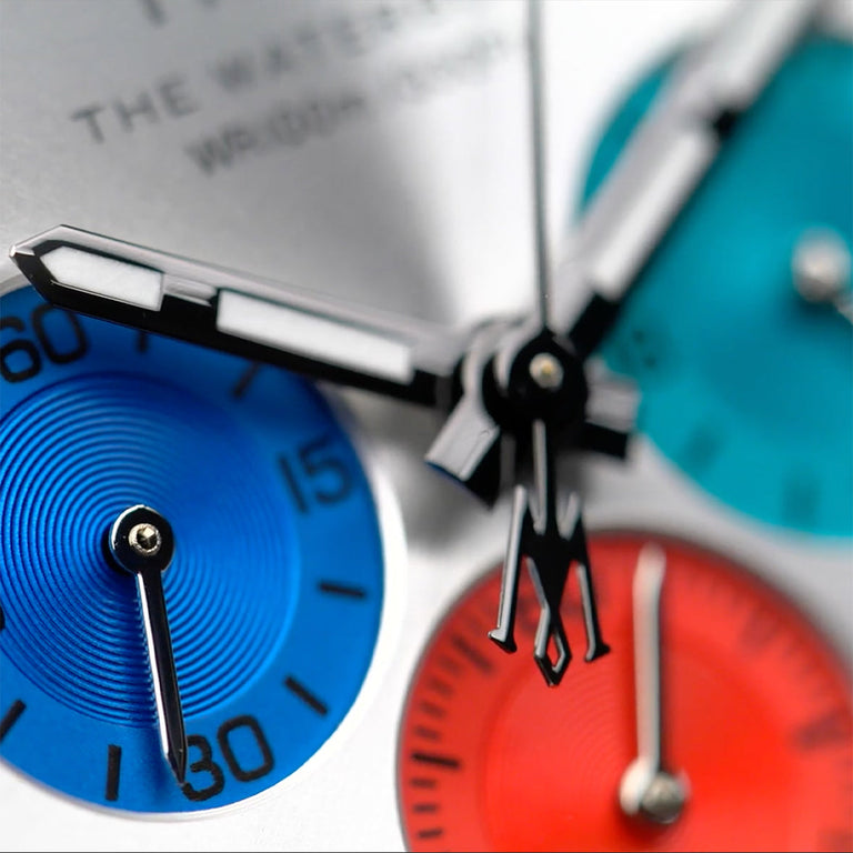 Macro detail of the Timex Waterbury Chronograph showing the red, blue, and teal chronograph sub-dials and polished hands with luminous accents.