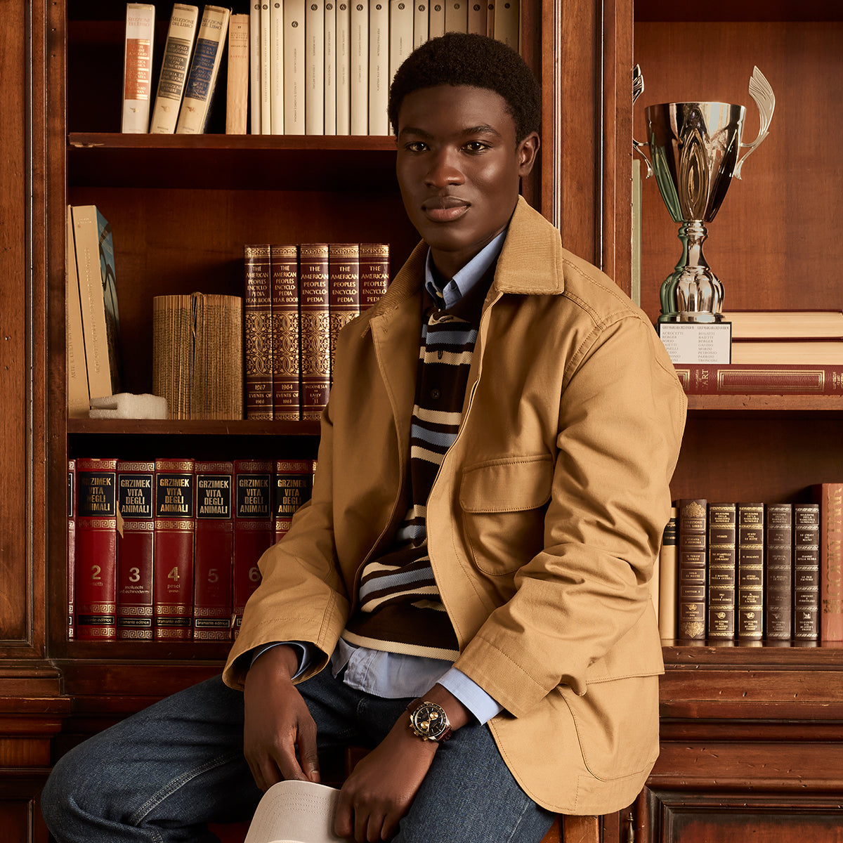 Man seated in a library wearing the Timex Waterbury Heritage Chronograph, styled with a casual jacket and striped sweater.