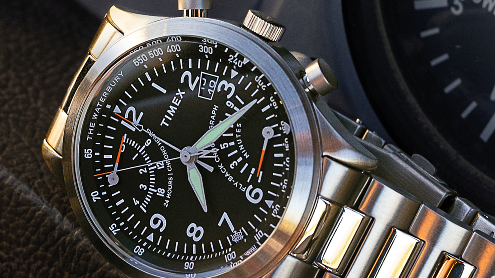 Macro close-up of the Timex Waterbury Traditional Fly-Back Chronograph black dial, showing luminous hands, sub-dials, and fly-back chronograph details.