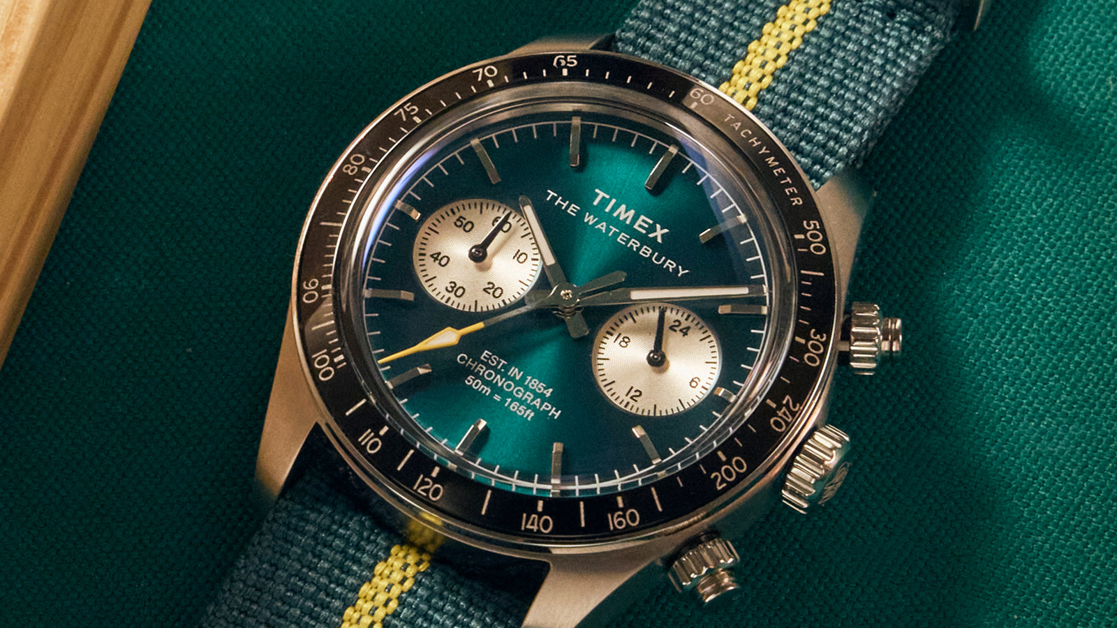Timex Waterbury Heritage Chronograph dial showing green face, silver chronograph sub-dials, and polished stainless-steel case.