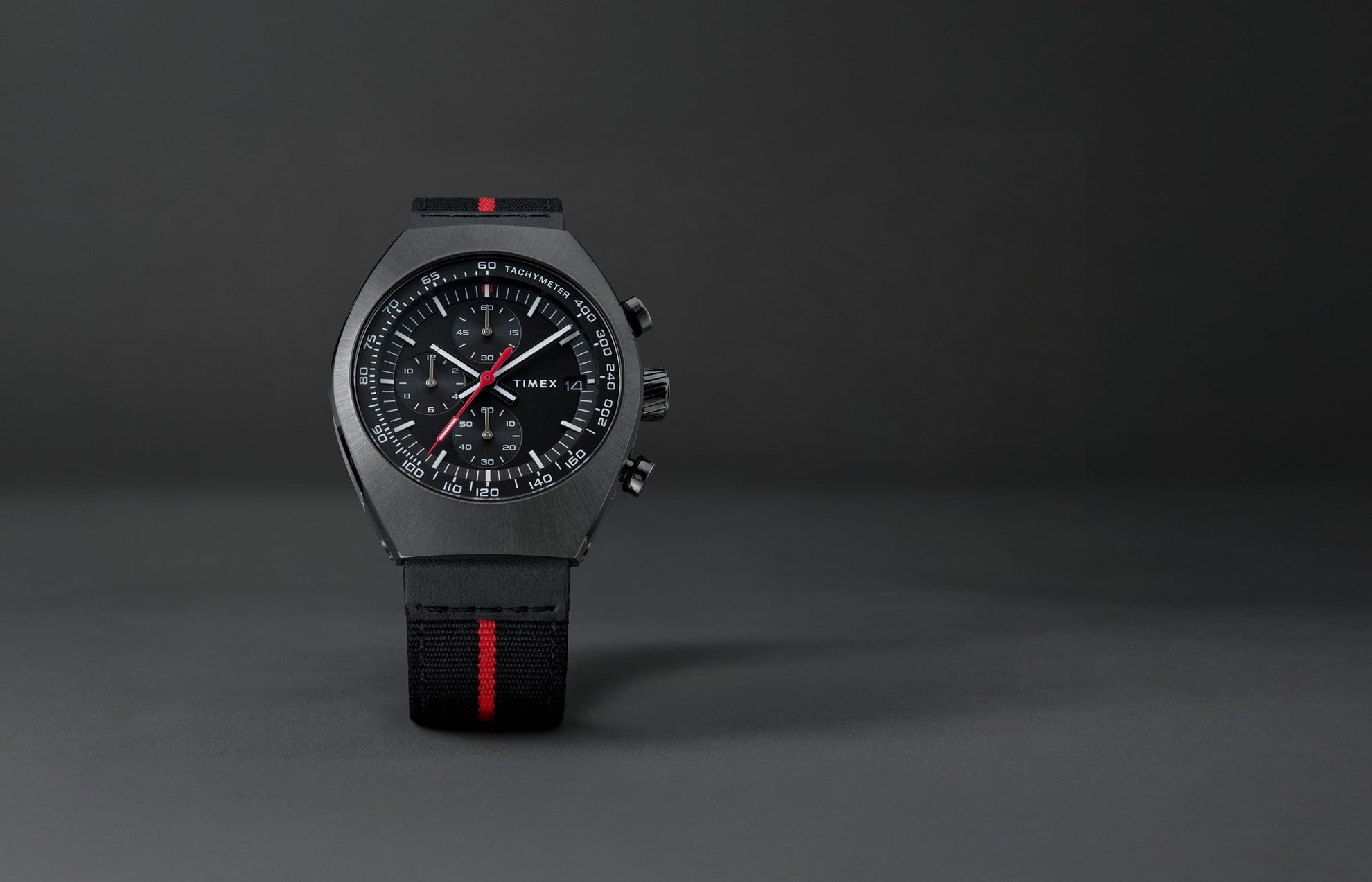 Front view of the Timex Legacy Tonneau Chronograph showing black dial with white markers, red seconds hand, and tachymeter scale.