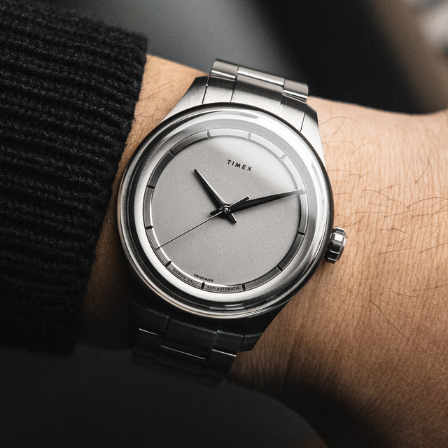 Timex Giorgio Galli S2Ti watch with a brushed titanium bracelet and clean silver dial, worn on wrist with a dark knit sleeve.