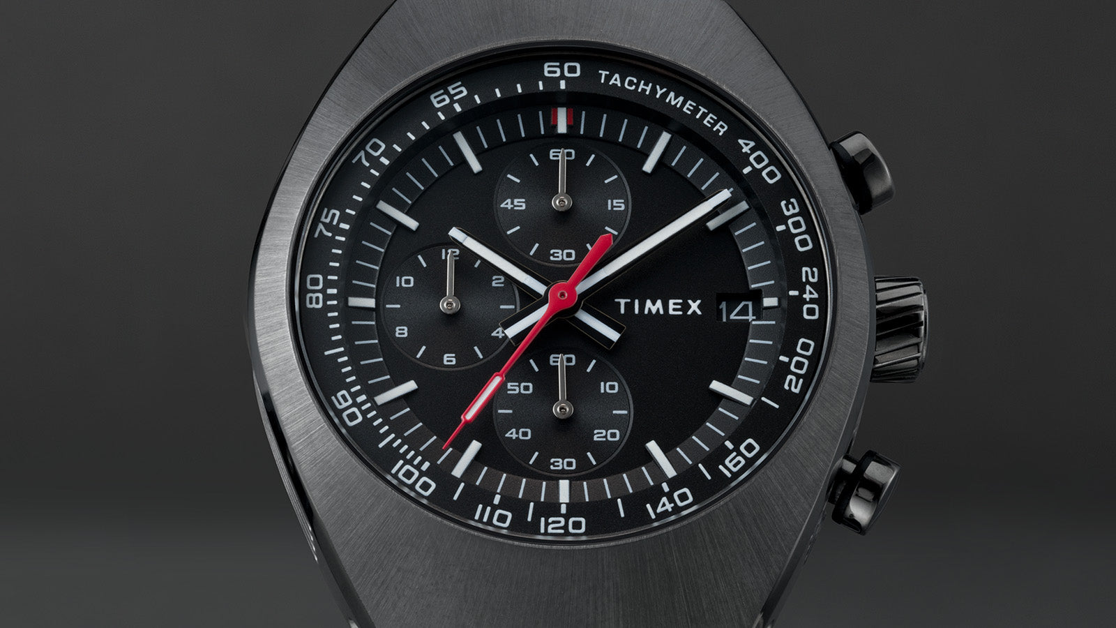 Front view of the Timex Legacy Tonneau Chronograph showing black dial with white markers, red seconds hand, and tachymeter scale.