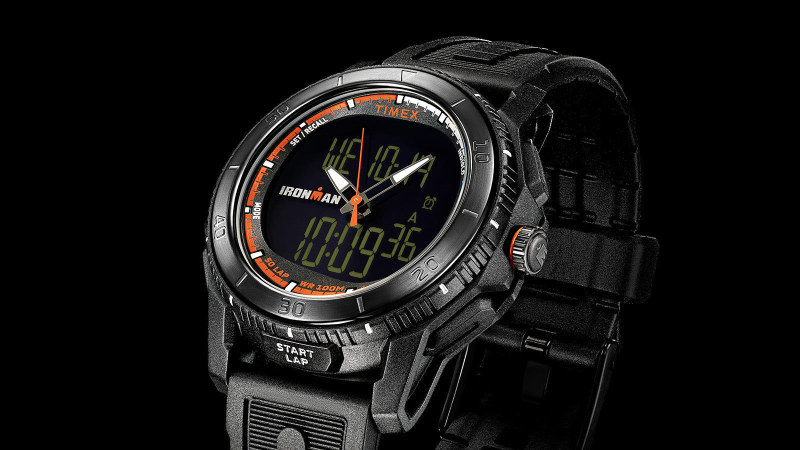 Macro view of the TIMEX® IRONMAN® Adrenaline Ana-Digi dial showing hybrid analog and digital layout with orange details and 100-meter water resistance marking.