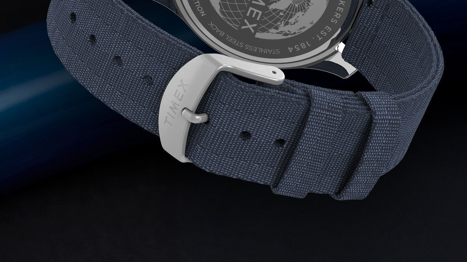 Close-up of the blue fabric strap and stainless-steel buckle engraved with “Timex,” attached to the Harborside Coast watch case.