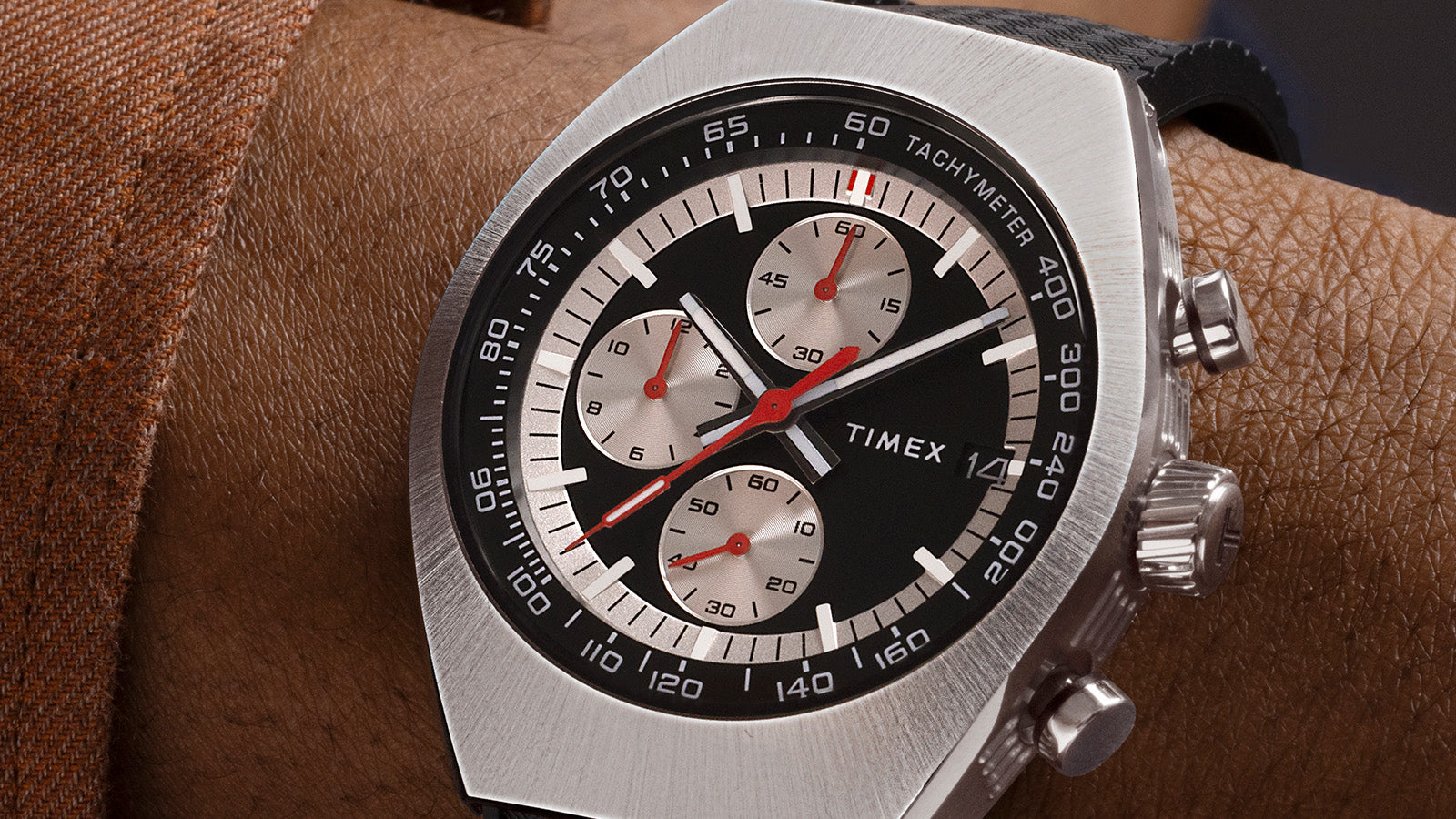 Close-up of the TIMEX® Legacy Tonneau Chronograph on wrist, highlighting the black and silver dial with red chronograph hands and tachymeter scale.