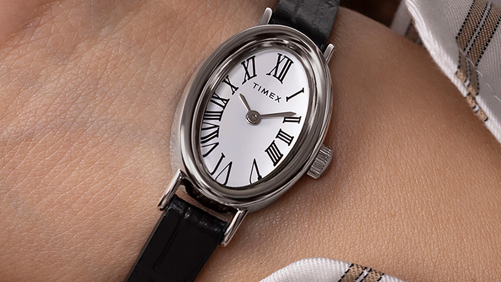 Close-up of the TIMEX® Cavatina watch on wrist, focusing on the white dial with black Roman numerals and silver-tone hands.