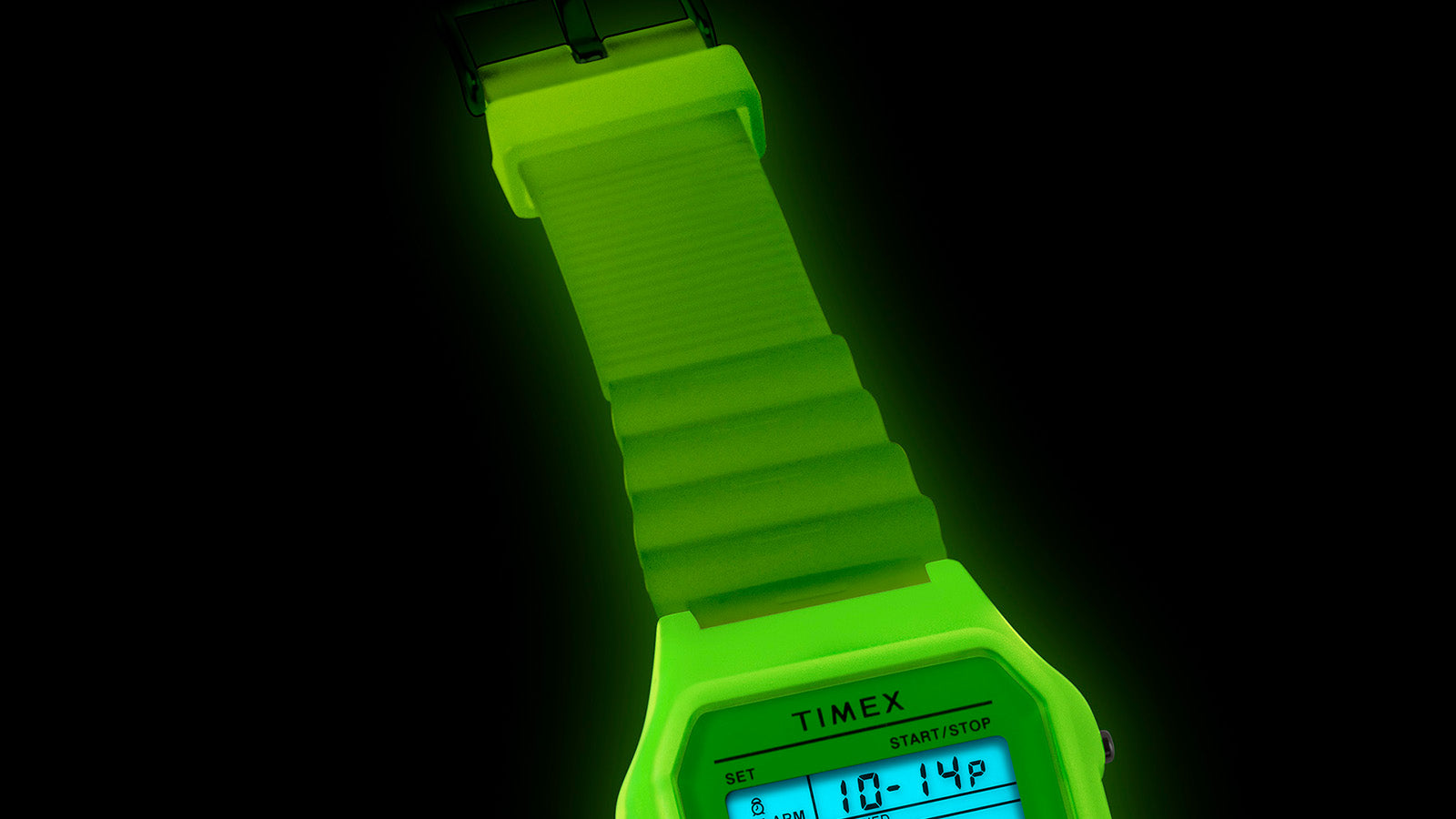 Close-up of the TIMEX® T80’s green resin strap glowing under the INDIGLO® light, highlighting its ridged texture and translucent finish.