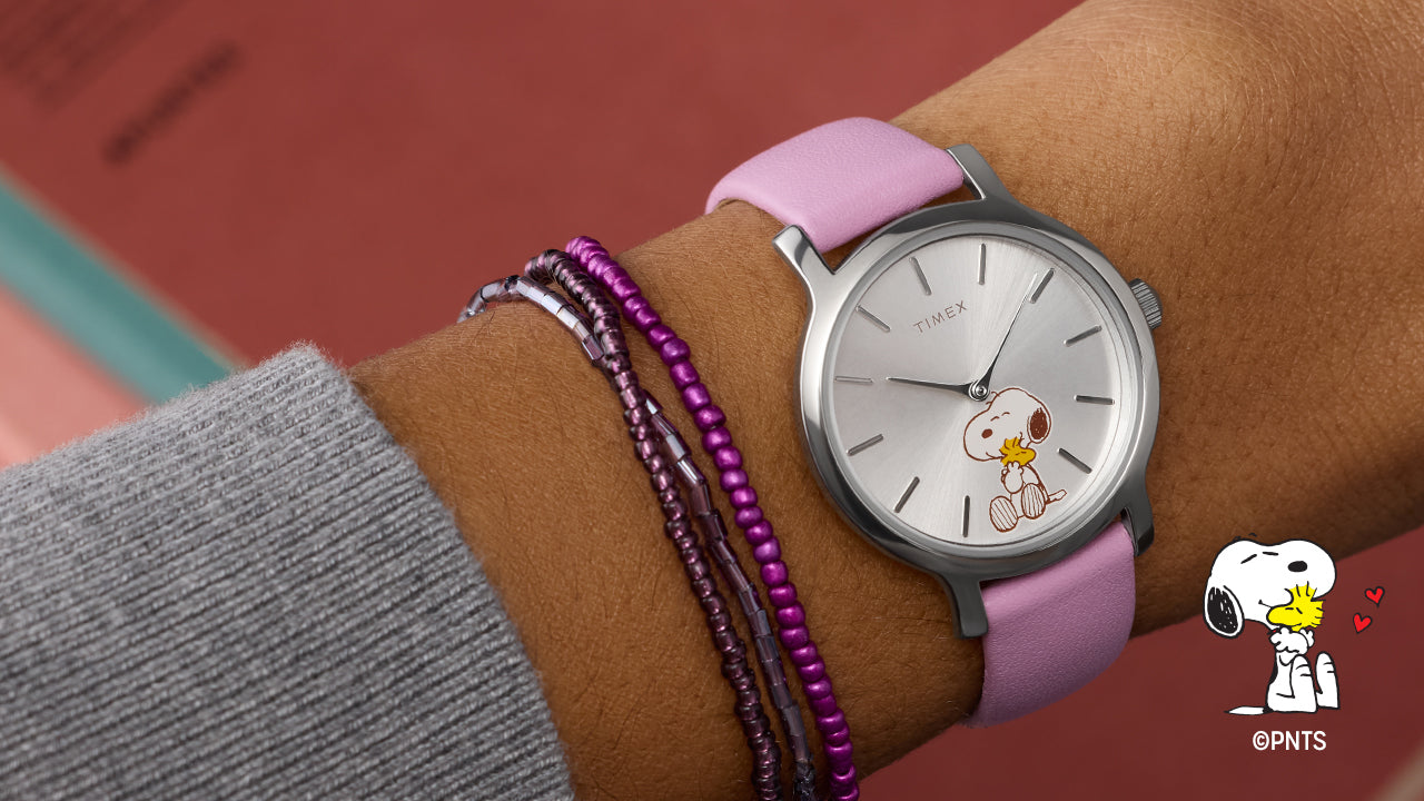 Peanuts® x Timex Transcend Snoopy Hug watch worn on wrist, featuring a silver dial with Snoopy hugging Woodstock and a soft pink leather strap.