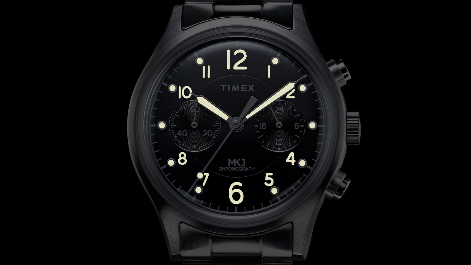 Close-up of Timex MK1 Chronograph black dial featuring luminous hands, Arabic numerals, and dual chronograph subdials.