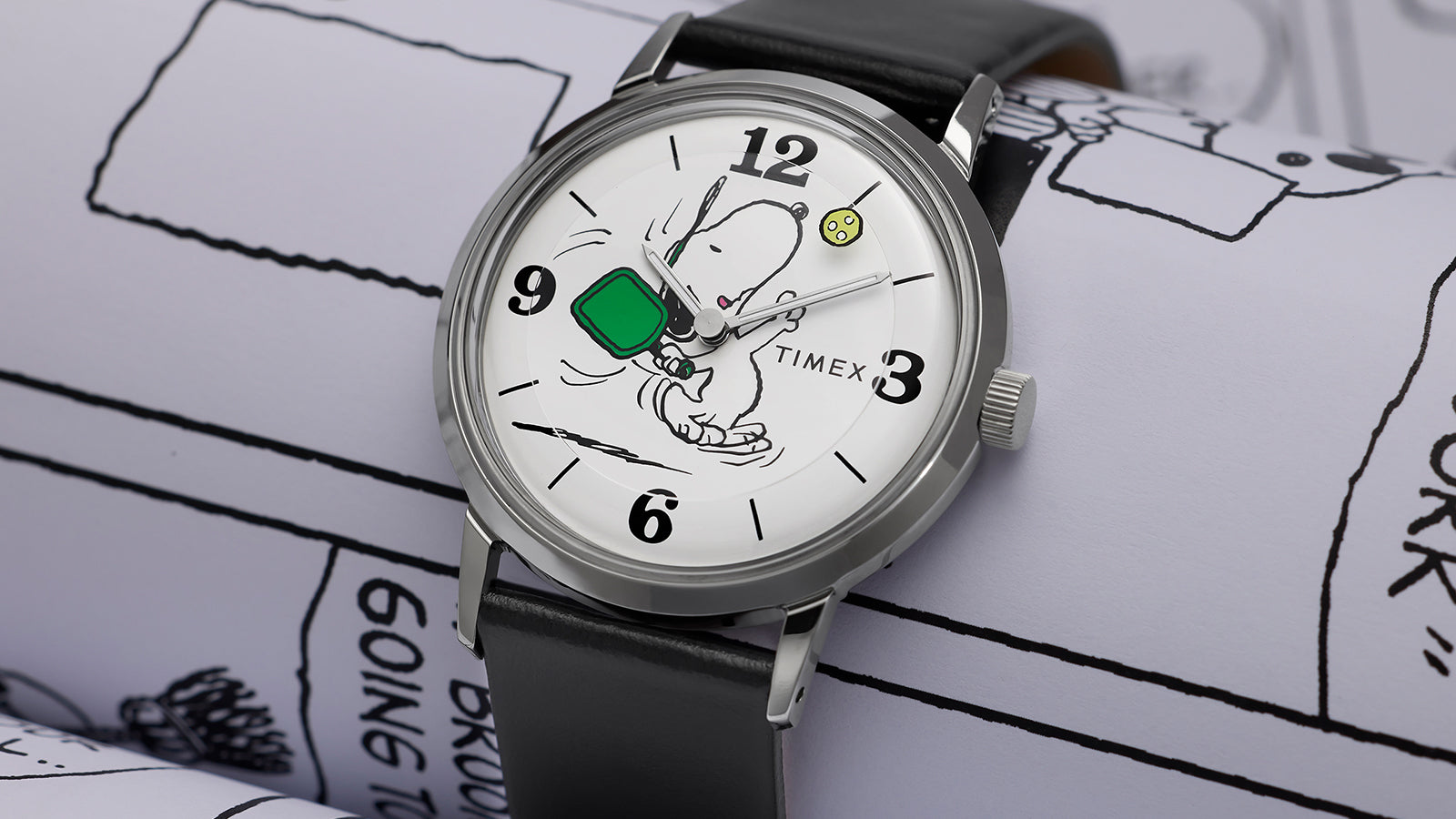 Angled view of Peanuts® x Timex Marlin® Pickleball Marlin® watch highlighting white Snoopy dial, polished stainless-steel case, and black leather strap.
