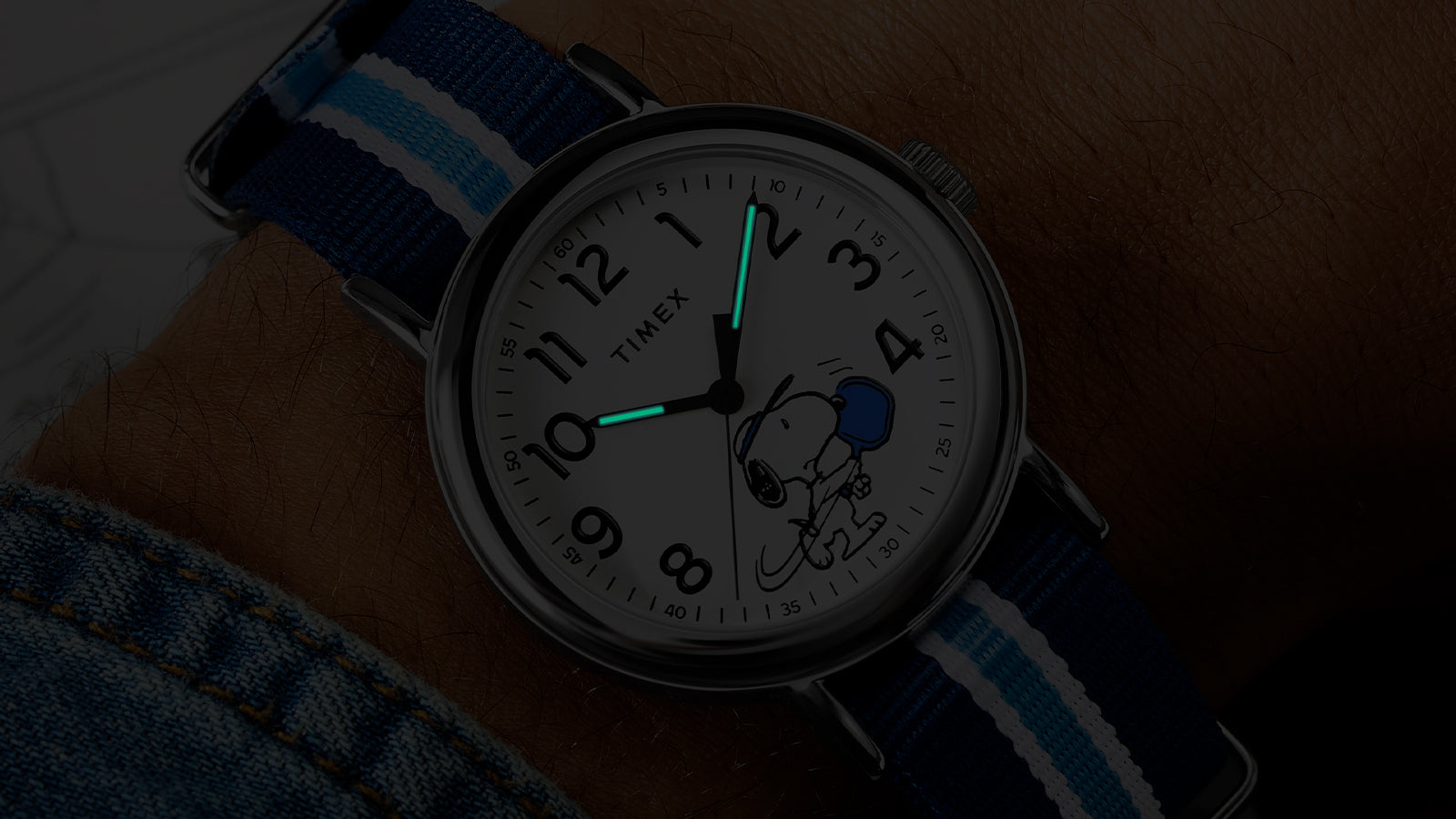 Peanuts® x Timex Weekender® Pickleball watch illuminated with INDIGLO® backlight, highlighting glowing hands and Snoopy pickleball dial artwork.