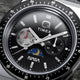 Close-up of Q Timex® x NASA black dial featuring day-of-week subdial with red hand, secondary subdial, moonphase detail, luminous markers, and NASA logo.