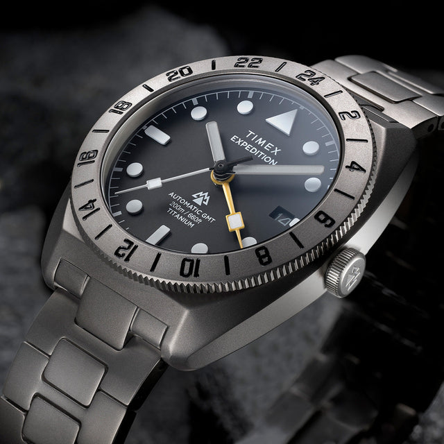 Close-up angled view of the Expedition® Pioneer Titanium Automatic GMT highlighting the black dial, luminous hour markers, date window, and yellow GMT hand.