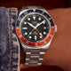 Top view of Timex Waterbury GMT automatic watch with stainless steel bracelet beside denim fabric.
