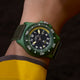 Angled wrist shot of Timex Expedition® Freedive Solar watch featuring green case, black textured dial, yellow second hand, and black fabric strap.