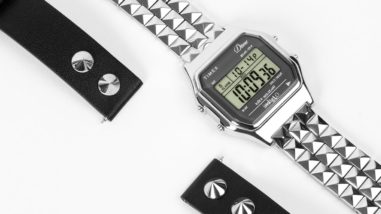 Timex x Dime digital watch with stainless steel pyramid-link bracelet and black studded leather strap on white background.