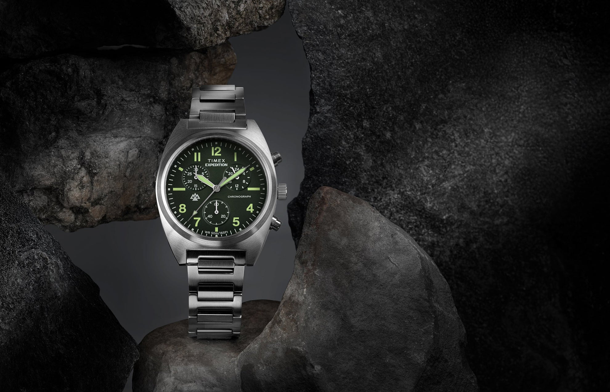 Timex Expedition Capstone Chronograph with green dial and stainless steel bracelet displayed on rocks