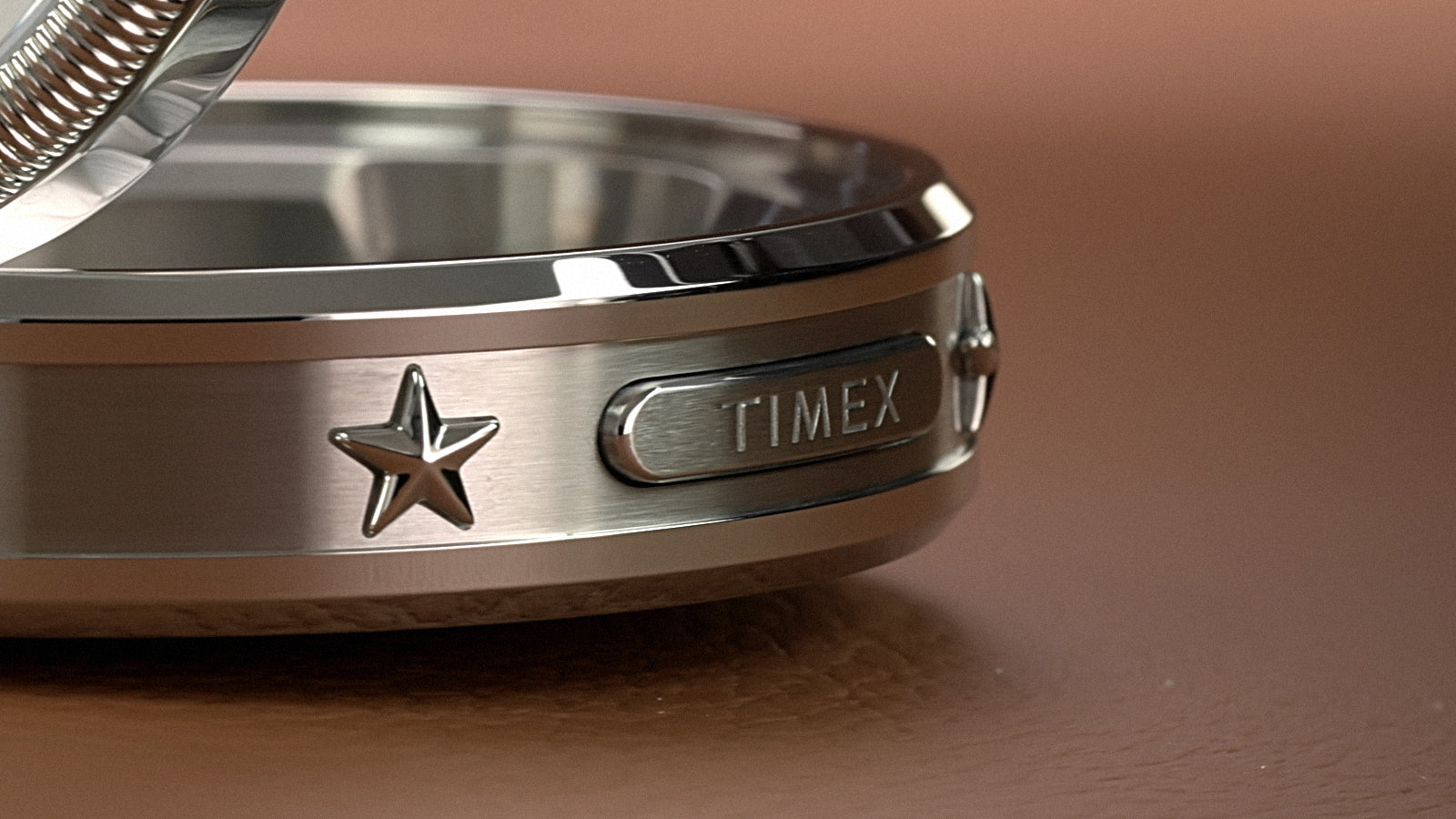 Close-up of the Waterbury America 250 Table Clock case featuring the Timex logo and star detailing on the brushed metal finish.
