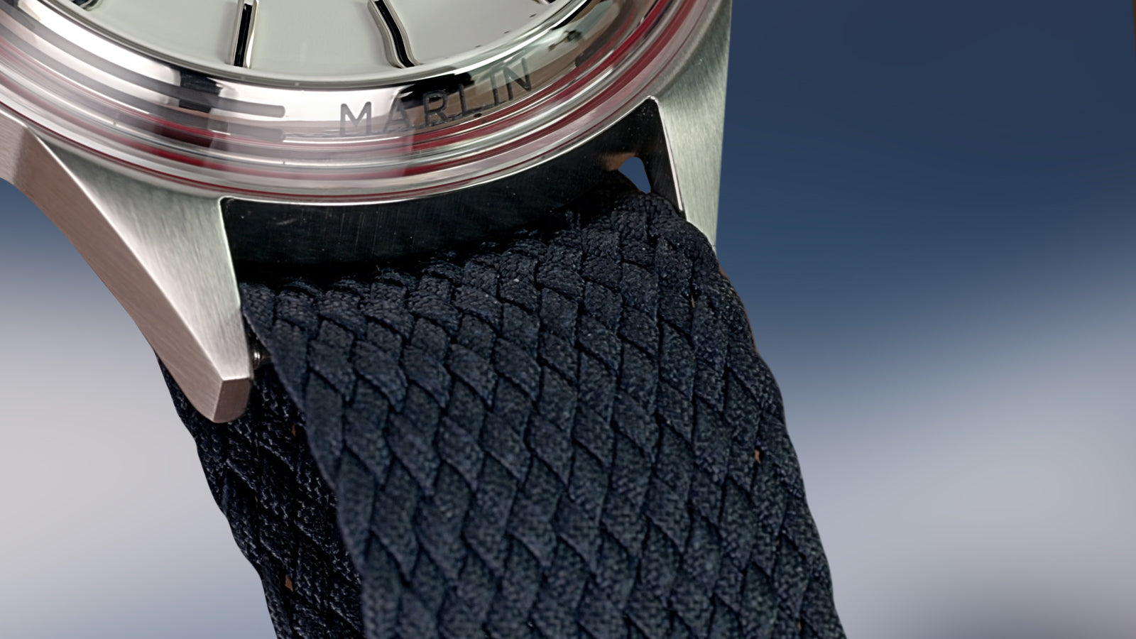 Close-up of the Marlin Jet America 250 blue woven strap and stainless-steel case with engraved Marlin branding.