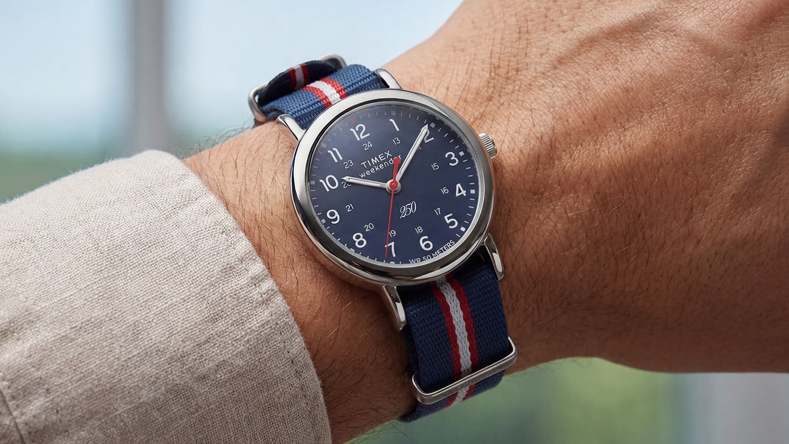 Weekender America 250 watch worn on the wrist, showcasing the blue dial and patriotic striped fabric strap.