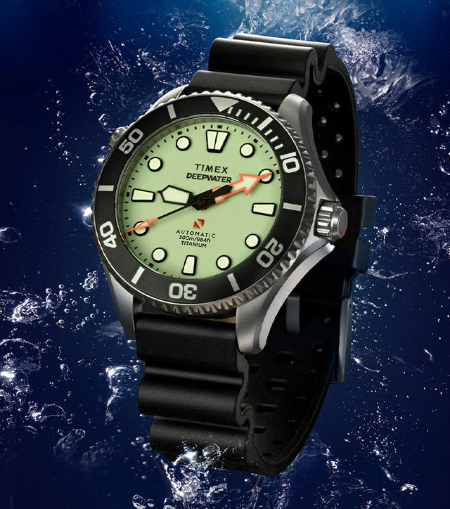 Timex Deepwater Meridian 300 Titanium HEV Automatic dive watch with full-lume dial and black rubber strap suspended in an underwater scene with rising bubbles.